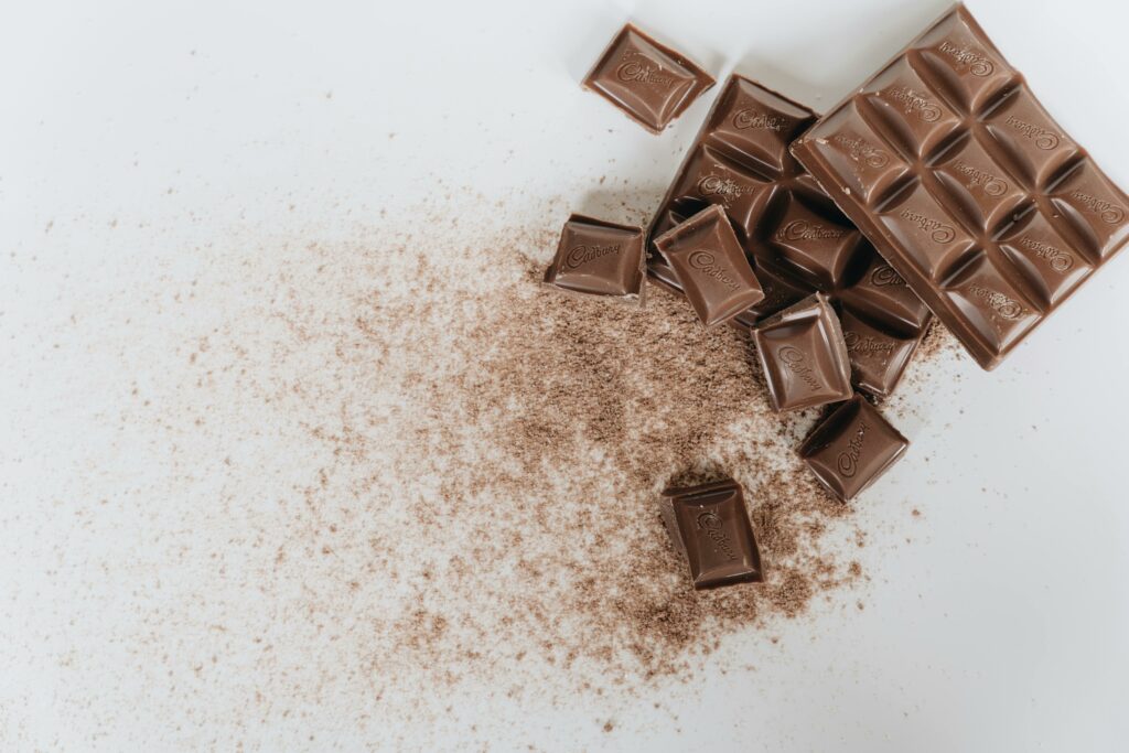 pexels-photo-4113296-4113296 Tantalizing image of assorted chocolate bars and cocoa powder on a clean white background.