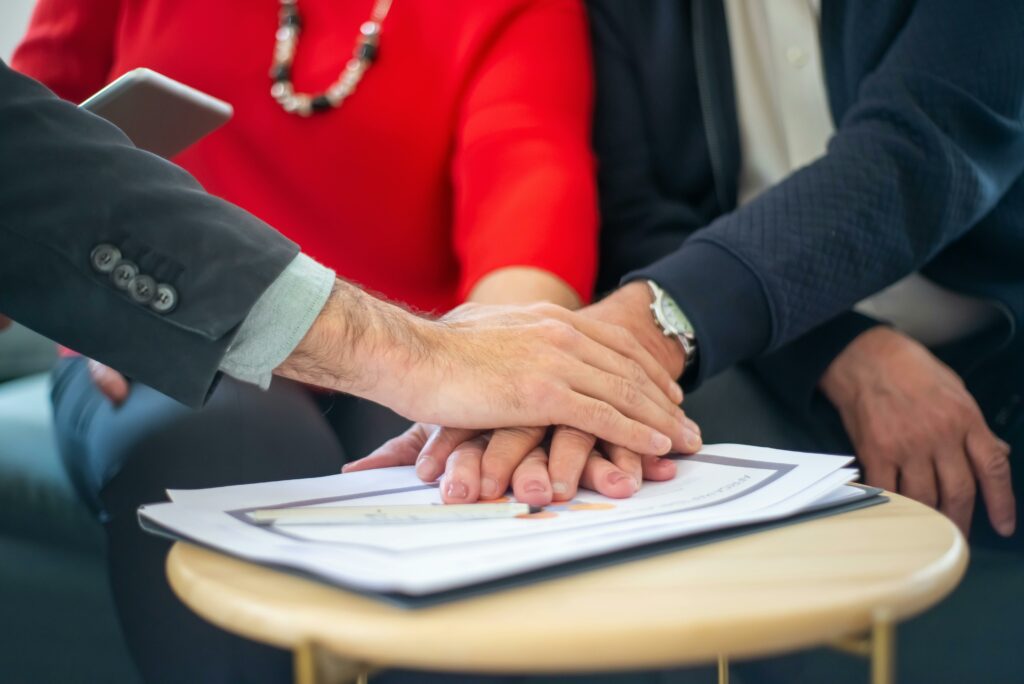 pexels-photo-8439685-8439685 Business professionals collaborating, with hands united over important documents, symbolizing teamwork and unity.