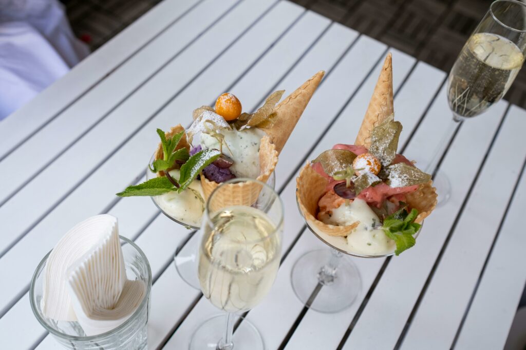 Glass cups of ice cream with mint leaves and champagne on a white table.